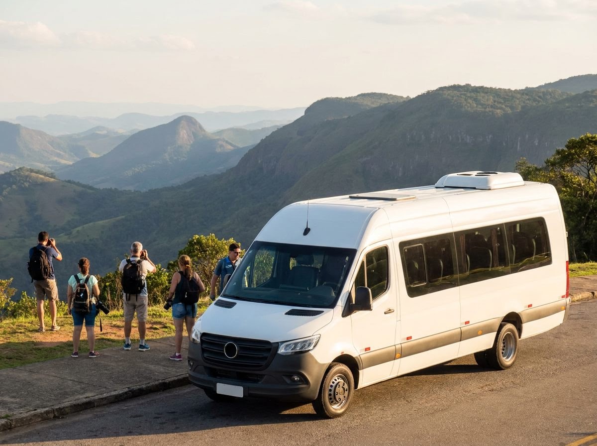 Micro-ônibus de turismo branco parado num mirante de serra, com um grupo pequeno fotografando a paisagem.